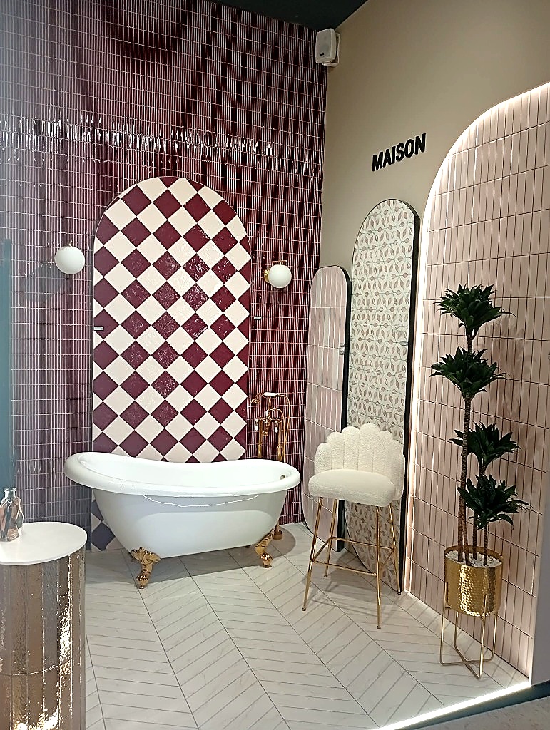 Bagno allestito da Monopole con rivestimento a scacchi bordeaux e bianco, vasca vintage e sedia a forma di mano dorata